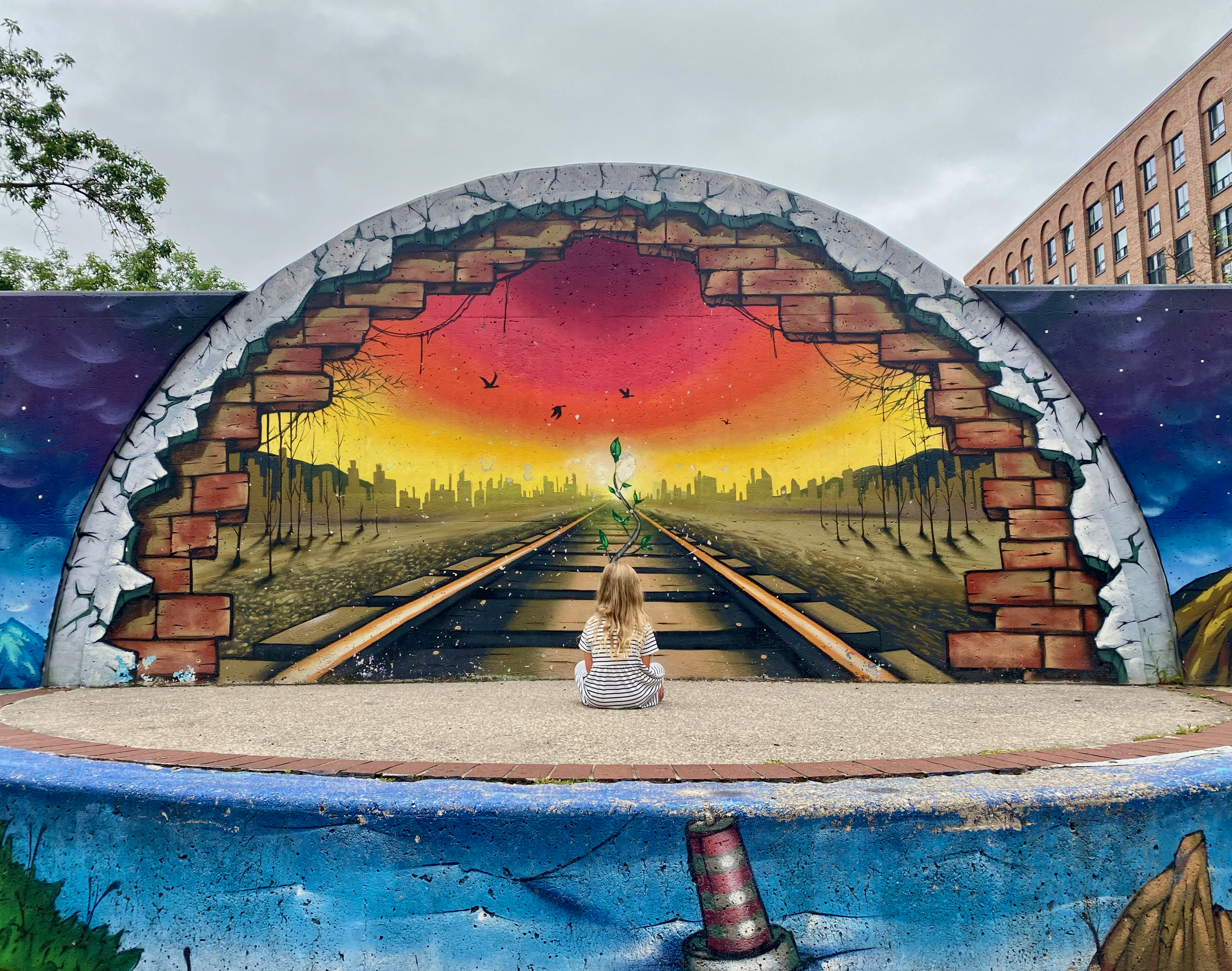 A colorful mural showing a child looking toward a brighter city
